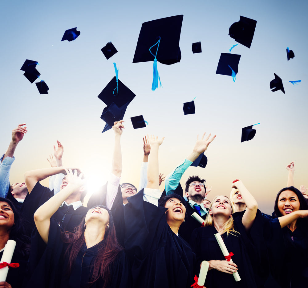 A group of college graduates throwing their caps in the air.  eventclothing.com