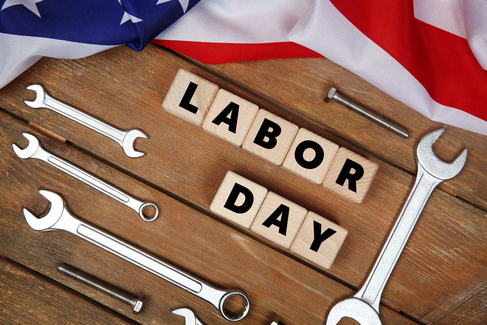 Wooden cubes with the words ‘labor day’ imprinted on them with wrenches and the American flag on a table. eventclothing.com